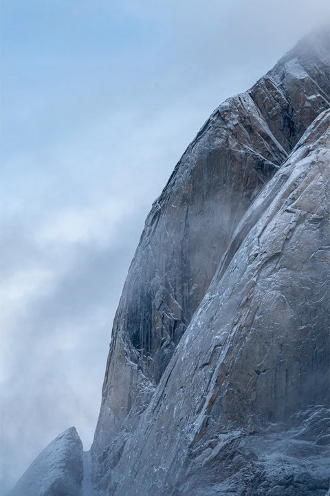 Frost-covered granite cliff face rising into cloud, Scoresbysund, Greenland, fine art landscape photograph by Peter Cox