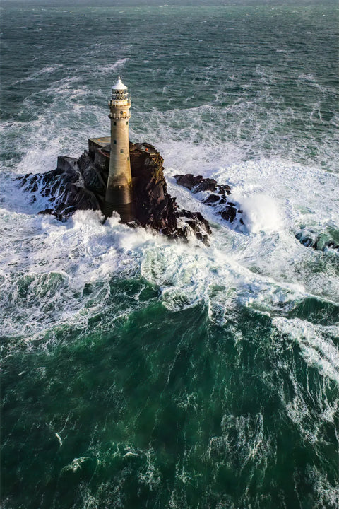 Aerial view of Fastnet Lighthouse on its rock surrounded by enormous storm waves and deep green Atlantic water, Cork