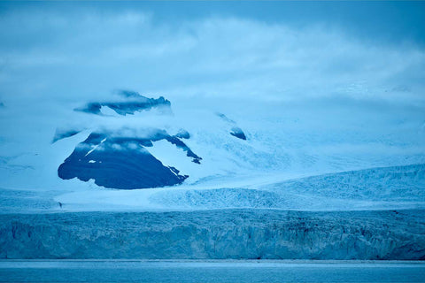Vast fractured blue ice face of the Nordenskjold Glacier rising toward cloud-wrapped snow-covered peaks in South Georgia