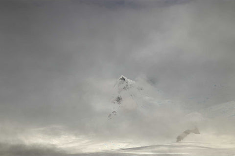 Mountain peak floating above a sea of fog in Charlotte Bay on the Antarctic Peninsula with soft diffused polar light
