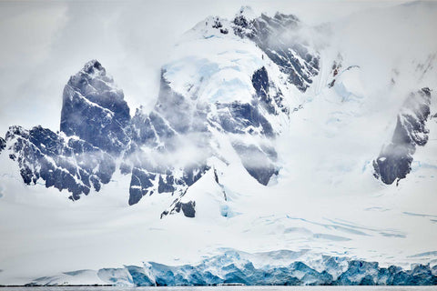 Snow-capped cliffs rising from icy waters at Cuverville Island, Antarctic Peninsula, fine art landscape photograph by Peter Cox