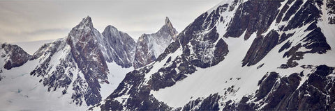 Sharp serrated mountain peaks dusted with snow towering against a muted sky at King Haakon Bay in South Georgia