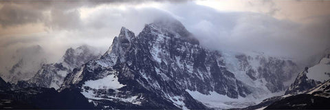 Snow-dusted jagged peaks rising from swirling mist at Fortuna Bay in South Georgia with light catching the icy ridges