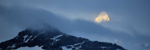 Mountain peak at St. Andrew's Bay in South Georgia partially shrouded in mist with a beam of light illuminating the summit
