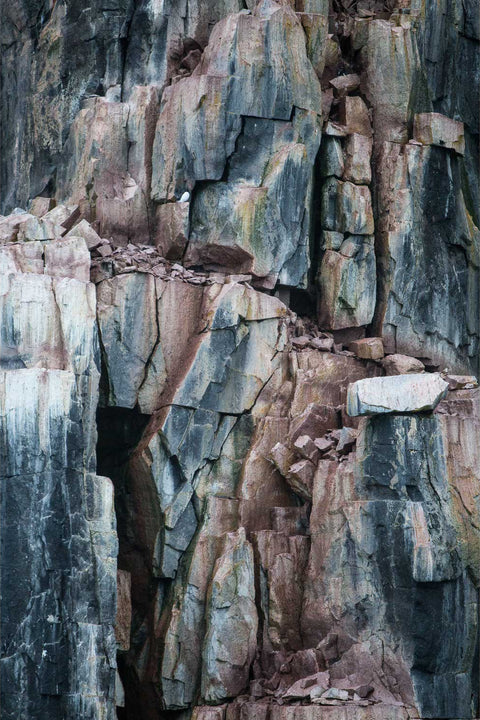 Alkafjellet bird cliff in Svalbard, layered rock strata in grey, pink, and ochre, fine art photograph by Peter Cox