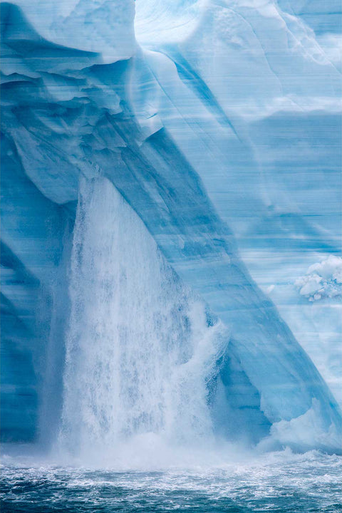 Meltwater cascading down the vivid blue face of the Brasvellbreen ice wall into the Arctic sea, Svalbard