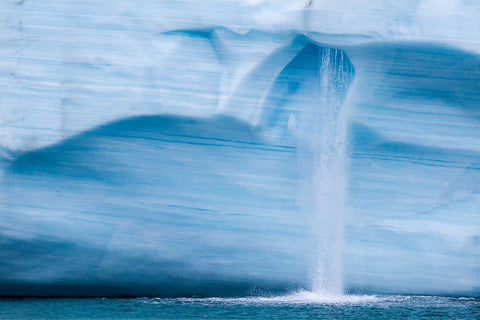 Delicate waterfall streaming down layered blue ice on the Brasvellbreen ice wall, Svalbard