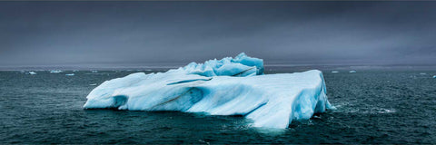 Lone iceberg drifting beneath stormy Arctic skies in Svalbard — fine art landscape photograph by Peter Cox