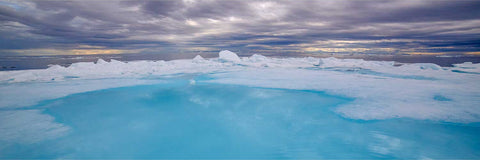 Sapphire-blue meltwater pooling on an Arctic ice floe under moody skies in Svalbard — fine art landscape photograph by Peter Cox