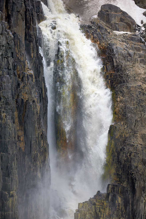 Glacial meltwater waterfall plunging down the rugged cliffs of Alkefjellet, Svalbard