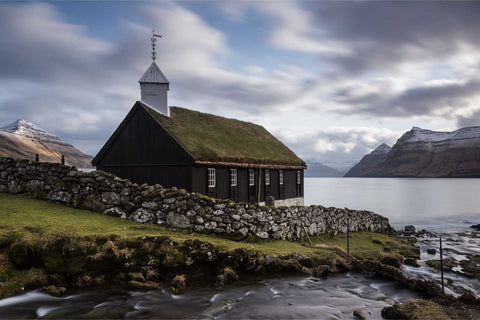 Black timber church with grass roof beside fjord, Funningur, Faroe Islands, fine art landscape photograph by Peter Cox