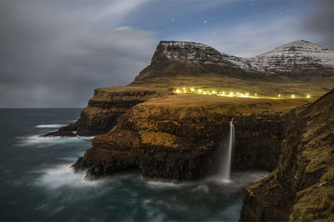 Gasadalur waterfall at night with village lights and stars, Faroe Islands, fine art landscape photograph by Peter Cox