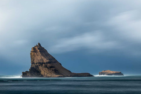 The dramatic silhouette of Tindholmur island rising sharply from the ocean in the Faroe Islands