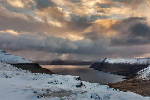 Snow-covered fjord at sunrise with rain squall, Funningfjordur, Faroe Islands, fine art landscape photograph by Peter Cox