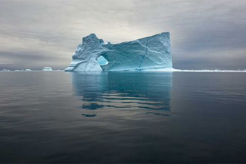 Arched iceberg sculpted by wind and sea in Scoresby Sound, Greenland — fine art landscape photograph by Peter Cox