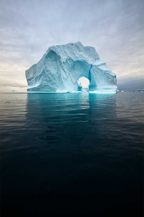 Grooved and arched iceberg floating in still waters of Scoresby Sound, Greenland — fine art landscape photograph by Peter Cox
