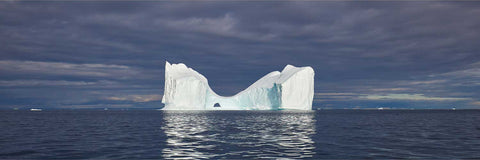 Pristine white iceberg glowing in soft evening light on calm Arctic waters, Greenland