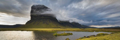 Mist-wreathed cliffs of Lomagnupur with shallow foreground pools reflecting dramatic evening sky, Iceland