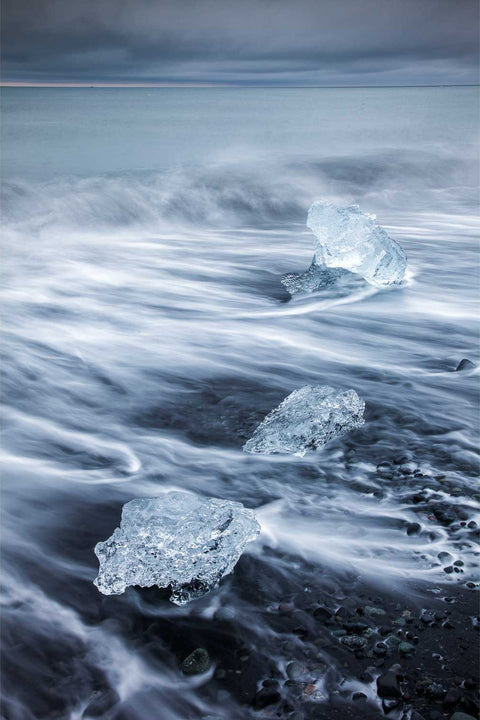 Glacial ice chunks on black sand with silky long exposure waves, Breidamerkursandur, Iceland — fine art landscape photograph by Peter Cox
