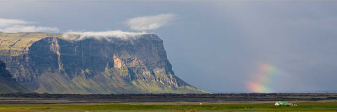 Storm light on the great cliffs of Lomagnupur with a rainbow beside them, south coast of Iceland
