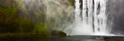 Skogafoss waterfall cascading down moss-covered cliffs surrounded by mist, southern Iceland