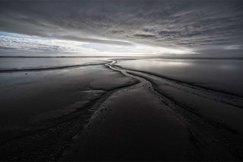 Meandering water channels reflecting the sky across dark sand at Stokksnes with Vestrahorn mountain in the distance, Iceland