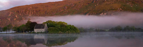 Morning mist rising over the calm lake at Gougane Barra with St. Finbar's Oratory and surrounding mountains, Cork