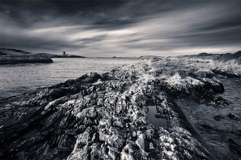 Ruined watchtower overlooking jagged rocks on the Mizen Peninsula coast, Cork, in black and white infrared