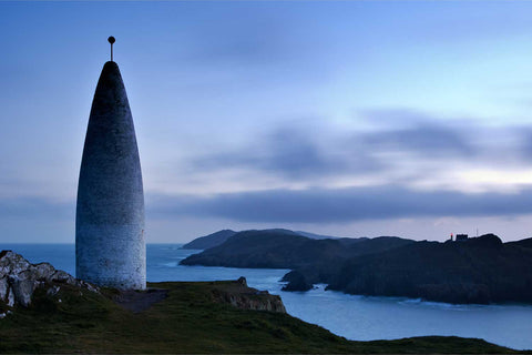 The Lot's Wife beacon at Baltimore harbour at dusk with Sherkin Island lighthouse winking red across the channel, Cork