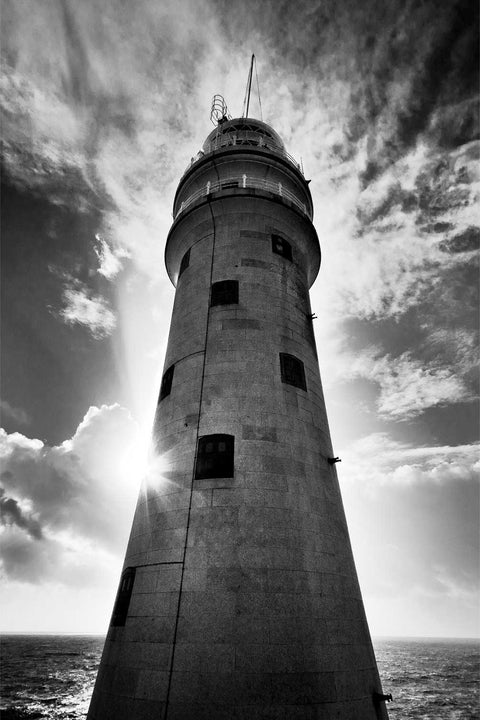 Black and white photograph of sunburst behind the Fastnet Lighthouse taken from the rock, Cork