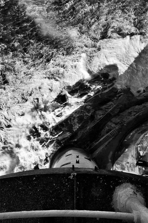 Vertiginous view looking down 140 feet from the Fastnet Lighthouse balcony to the seething waters below in black and white