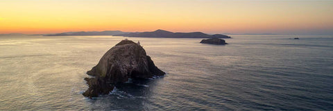 Aerial sunrise view of the Bull, Cow and Calf Rocks emerging from calm sea off the Beara Peninsula, Cork
