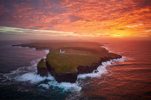 Aerial view of Loop Head lighthouse and cliffs at fiery sunrise, with the Shannon Estuary and Atlantic, County Clare