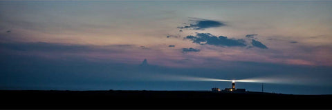 Tory Island Lighthouse beam sweeping through hazy night air on both sides of the tower in a long exposure on the Donegal coast