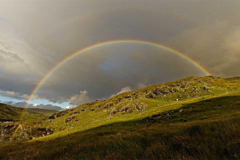 Intense double rainbow arching across the sky over green mountains near Glencolmcille in County Donegal