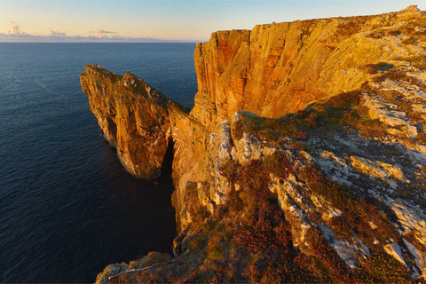 Sunset light bathing the dramatic sea cliffs of Dun Bhaloir promontory fort on Tory Island off the Donegal coast
