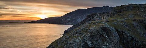 Slieve League cliffs rising behind a Napoleonic watchtower at sunset, County Donegal