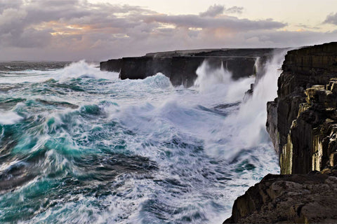 Enormous waves sending spray over 30-metre sea cliffs at Poll an tSeidein on Inis Meain, Aran Islands at sunset