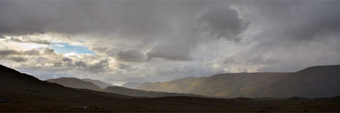 Dramatic light slicing through a stormy Connemara landscape on the road towards Leenaun village, County Galway