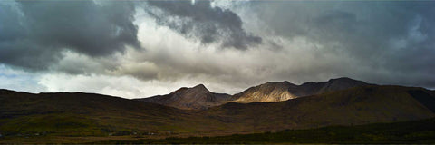 The Maumturk Mountains in Connemara lit by dramatic sunlight on a stormy day, County Galway