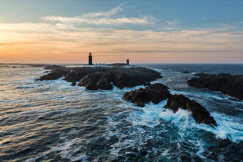 Aerial view of Slyne Head Lighthouse on rocky islands at sunrise with rough Atlantic seas, Galway