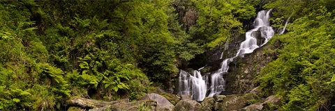 Torc Waterfall cascading through a leafy green valley in Killarney on an overcast day