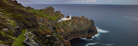 Panoramic night view of Skellig Michael lower lighthouse after moonrise with winding road through rugged island rock