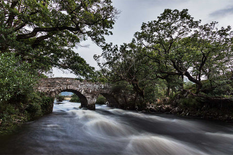 The Old Weir Bridge at twilight where three Killarney lakes converge, with soft fading light on still water