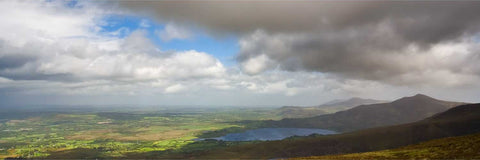Lough Guitane and surrounding green hills under dark brooding clouds near Mangerton Mountain, Kerry