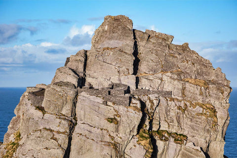 Ancient stone hermitage perched on the craggy peak of Skellig Michael against a clear blue sky, aerial view off the Kerry coast