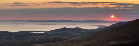 Soft orange and pink sunrise over the Maharees tombolo in Kerry with Loop Head peninsula on the distant horizon