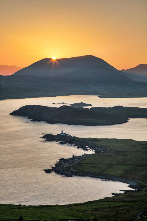 Golden sunrise over Valentia Island with Cromwell Point Lighthouse and the Kerry coastline seen from Geokaun mountain