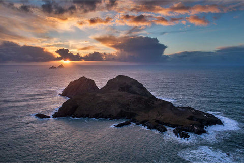 Aerial view of Puffin Island off the Kerry coast with the Skellig Islands silhouetted against a golden sunset