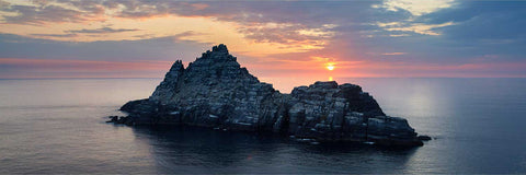 Aerial view of Small Skellig island covered in white gannets at sunset with orange and pink sky, Kerry